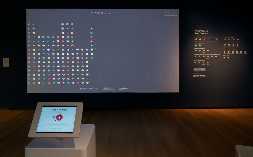 Photo of a portion of the interactive art installation "What Counts" by Giorgia Lupi. The displayed screen is labeled "Data Portraits".